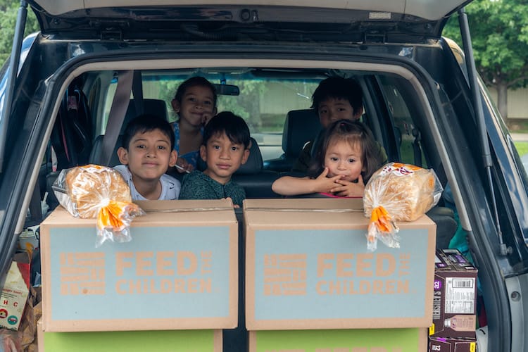 Children in the back of a card with boxes of food