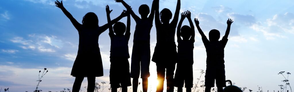 A group of children holding their hands in the air outdoors