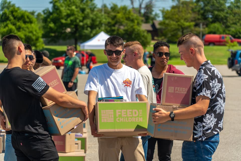 A group of men carrying boxes at an outdoor event