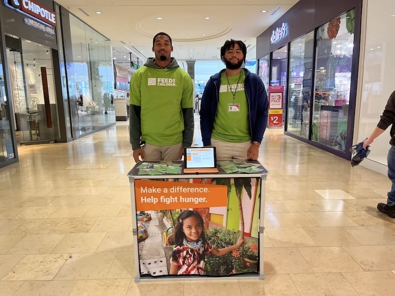 Two volunteers outdoors at a booth