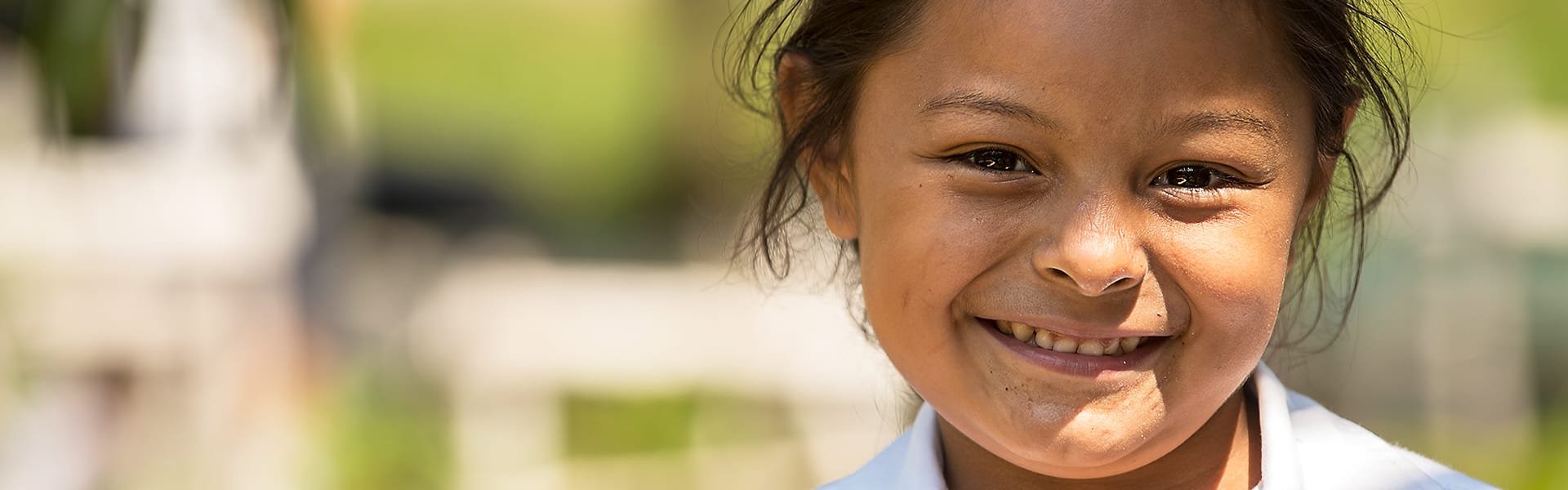 A child smiling outdoors in the sun