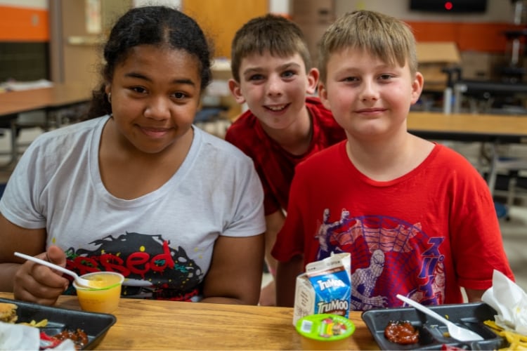 children sitting at a table in a cafeteria