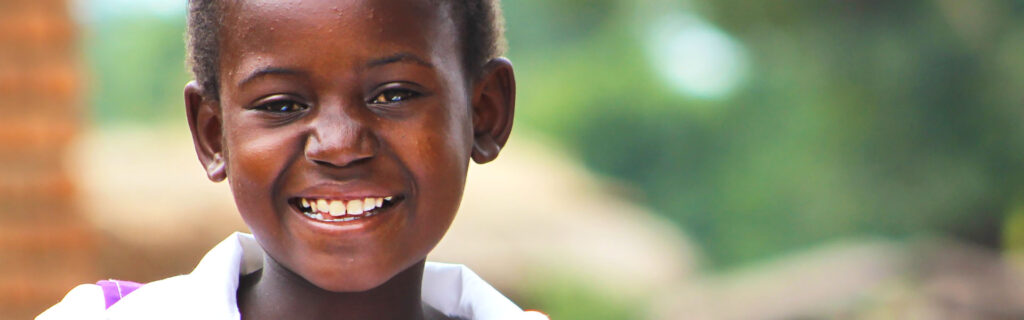 A child smiling outdoors in Malawi