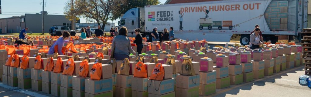 An outdoor event with boxes and volunteers standing in a parking lot