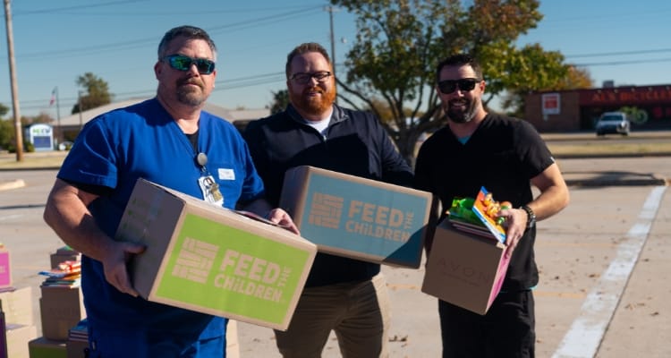 Three volunteers with boxes at an event