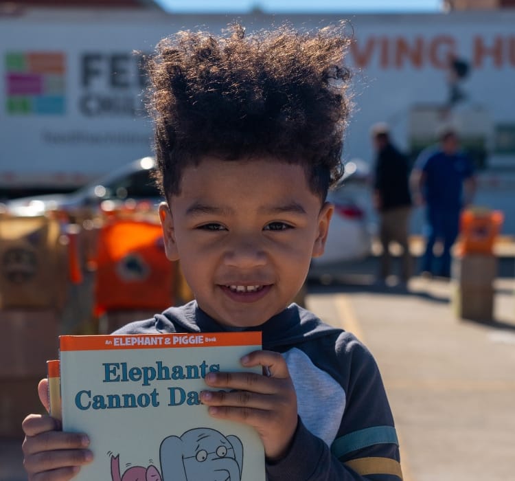 A child holding books at an outdoor event