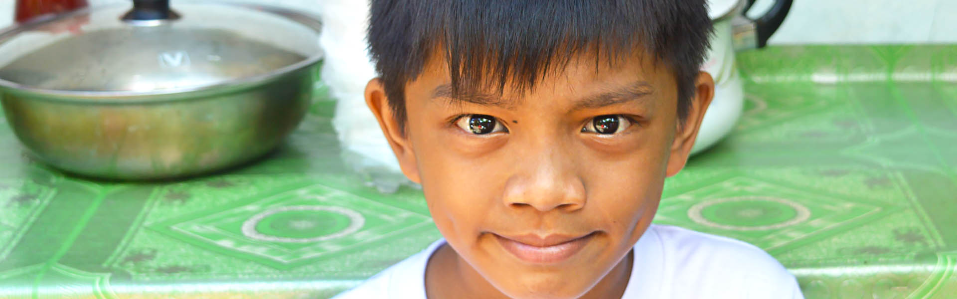 A child sitting next to a table in the Philippines