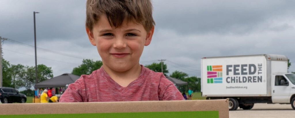 A boy holding a box at an outdoor event