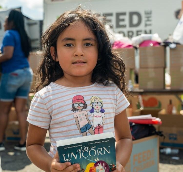 A girl holding a book at an outdoor event