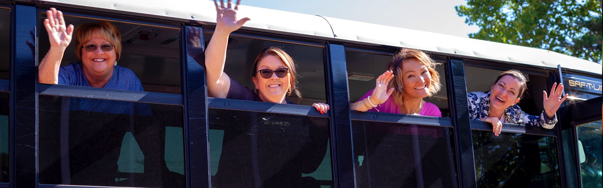 A group of teachers waving in the windows of a school bus