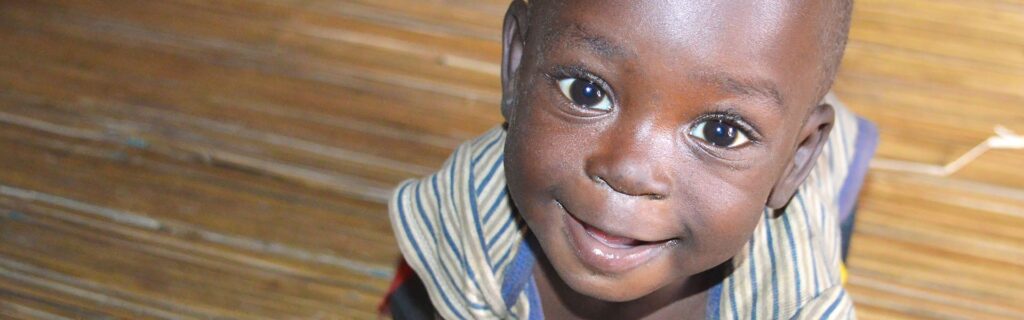 A small child smiling indoors in Uganda