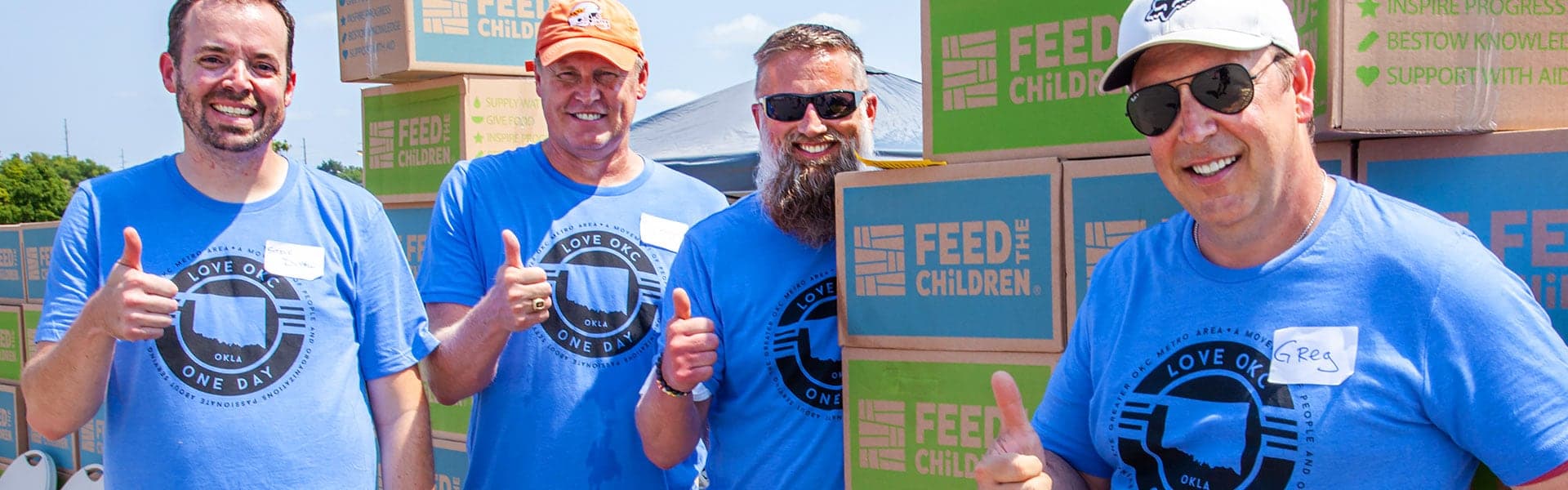 Volunteers smiling standing outdoors at a box event