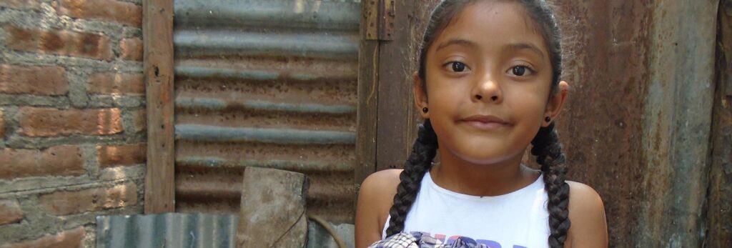 A young girl standing in front of the exterior of a building