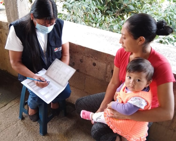 Anyeli being held by her mother with a feed the children member.