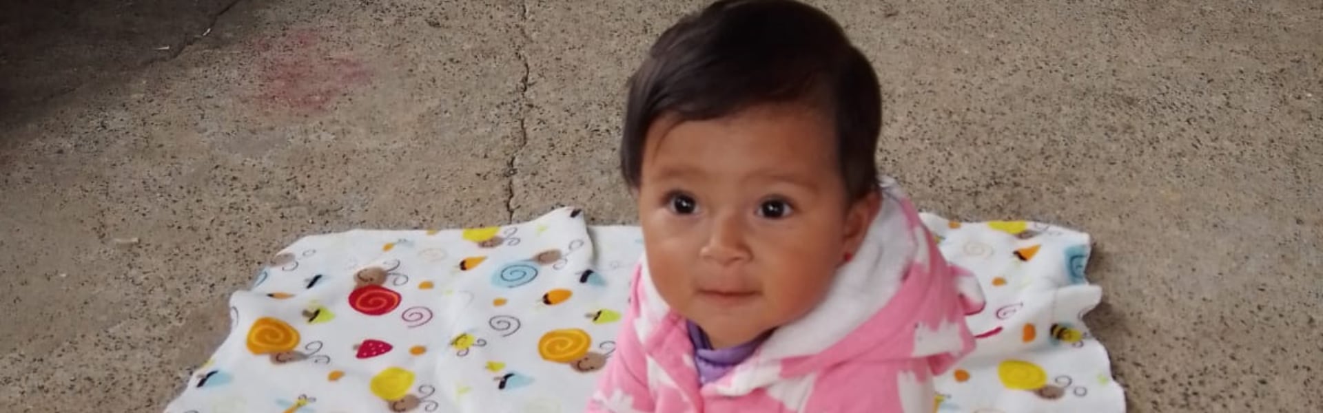 A toddler sitting on a blanket on the floor