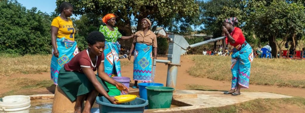 People getting water from a well outdoors