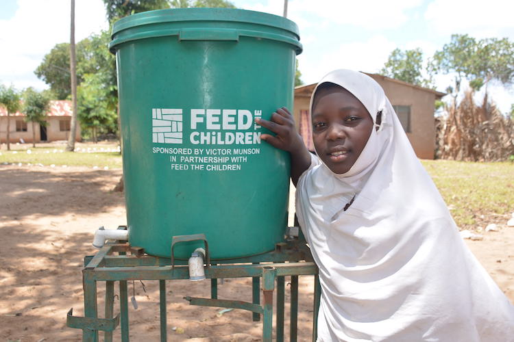 A young girl next to a water dispenser