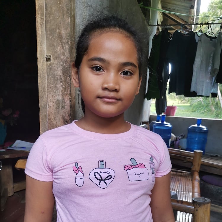 Child with a pink shirt standing indoors