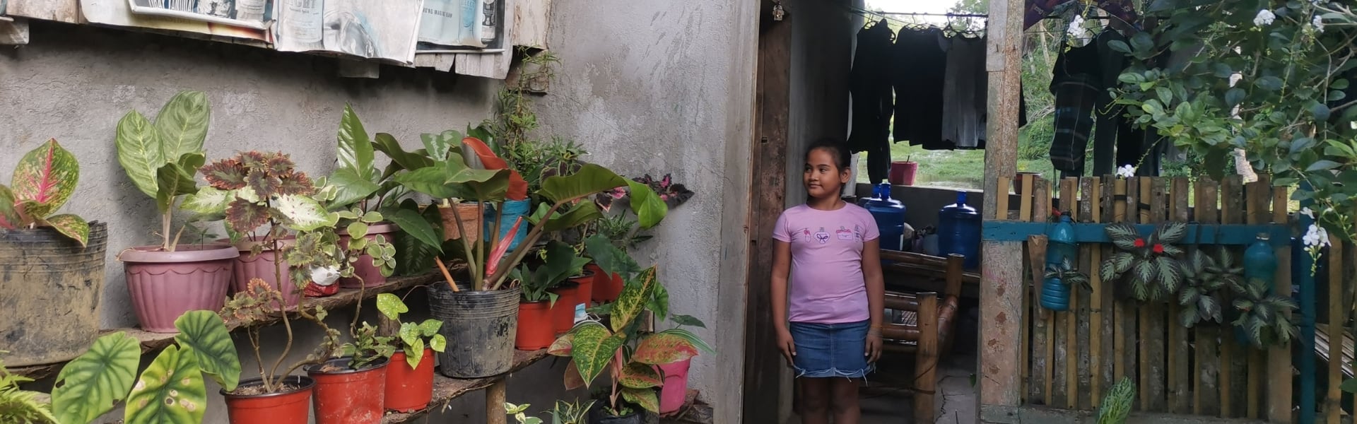 A child standing outside of a house with plants