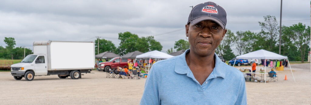 A man standing outdoors in front of event tents