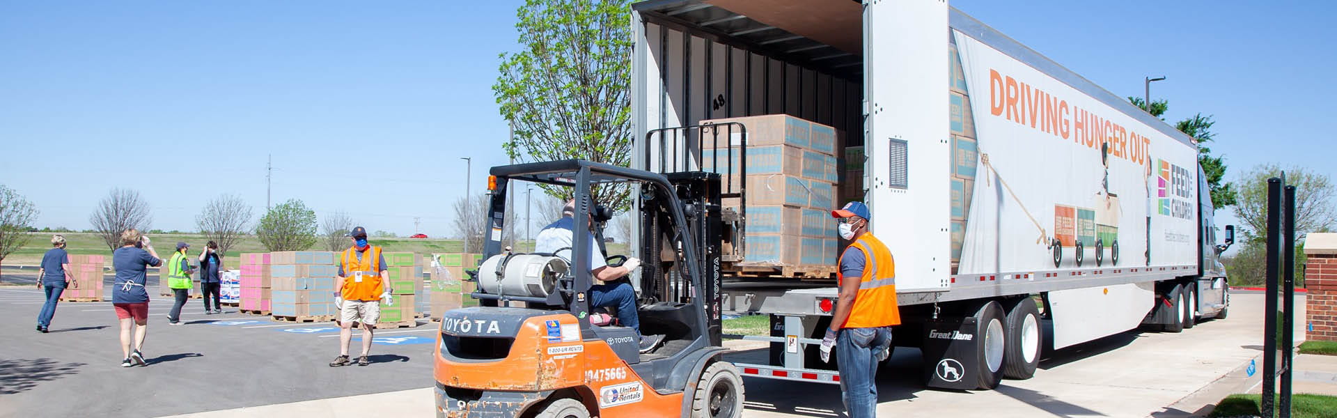 A forklift loading boxes into a feed the children semi