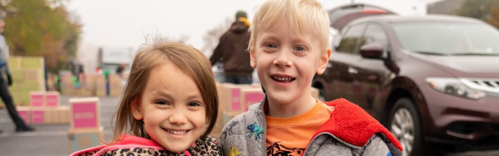 Two children smiling outdoors at an event