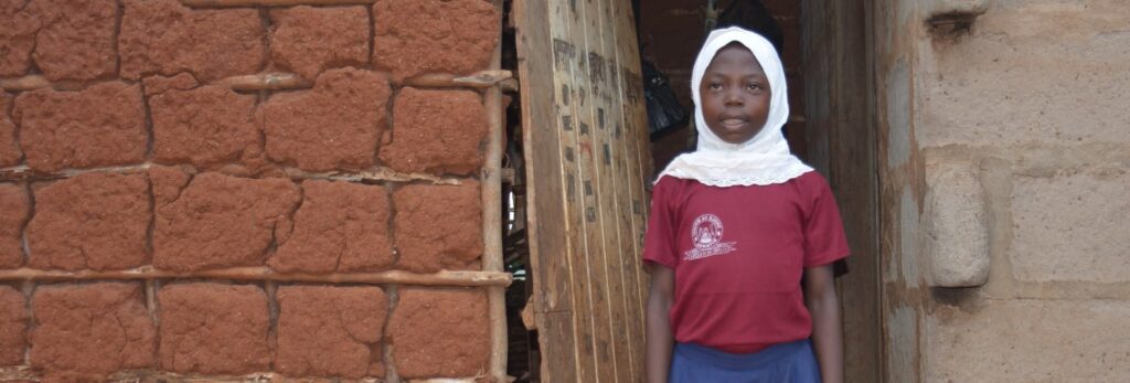 A young girl in Africa standing outside of a building