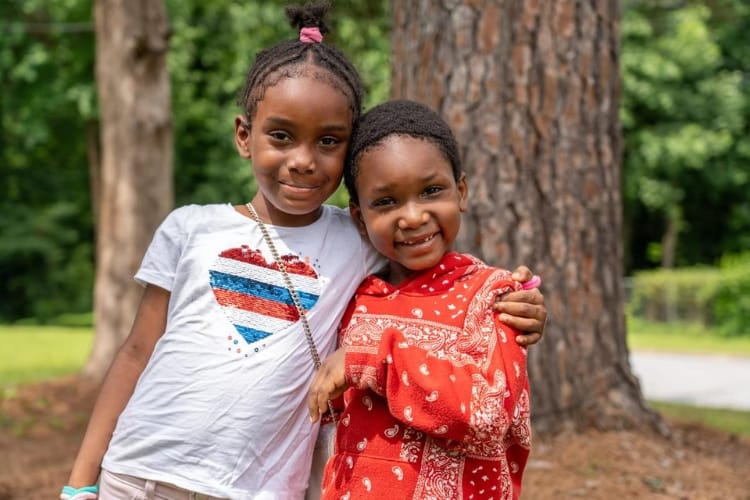 Two children hugging while standing outdoors