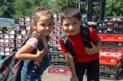 Two children with backpacks at an outdoor event
