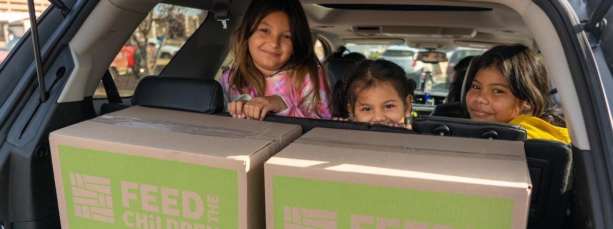 Children in the back of a car with food boxes