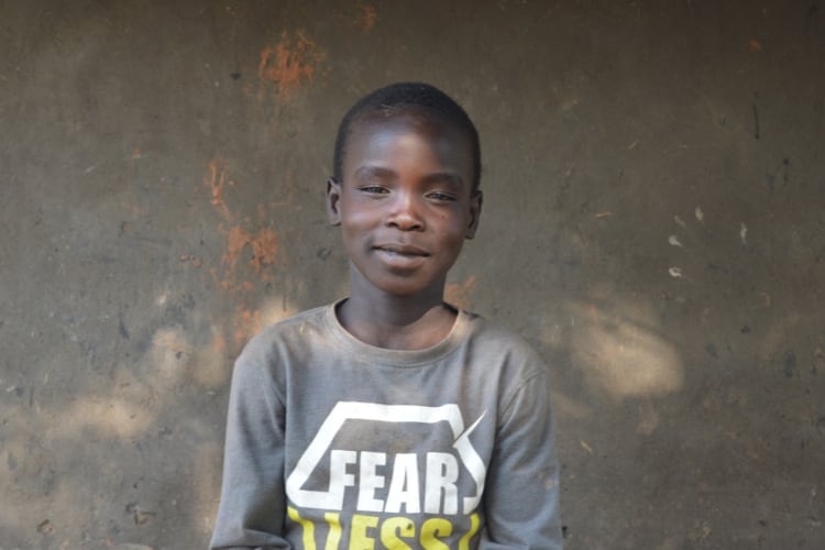 A boy smiling outdoors looking at camera