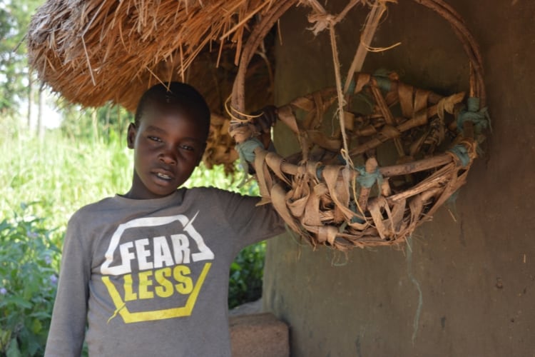 A boy standing next to his house with a basket