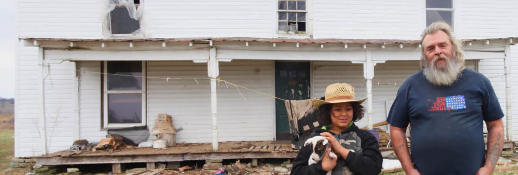 A man and boy with a dog standing in front of a house