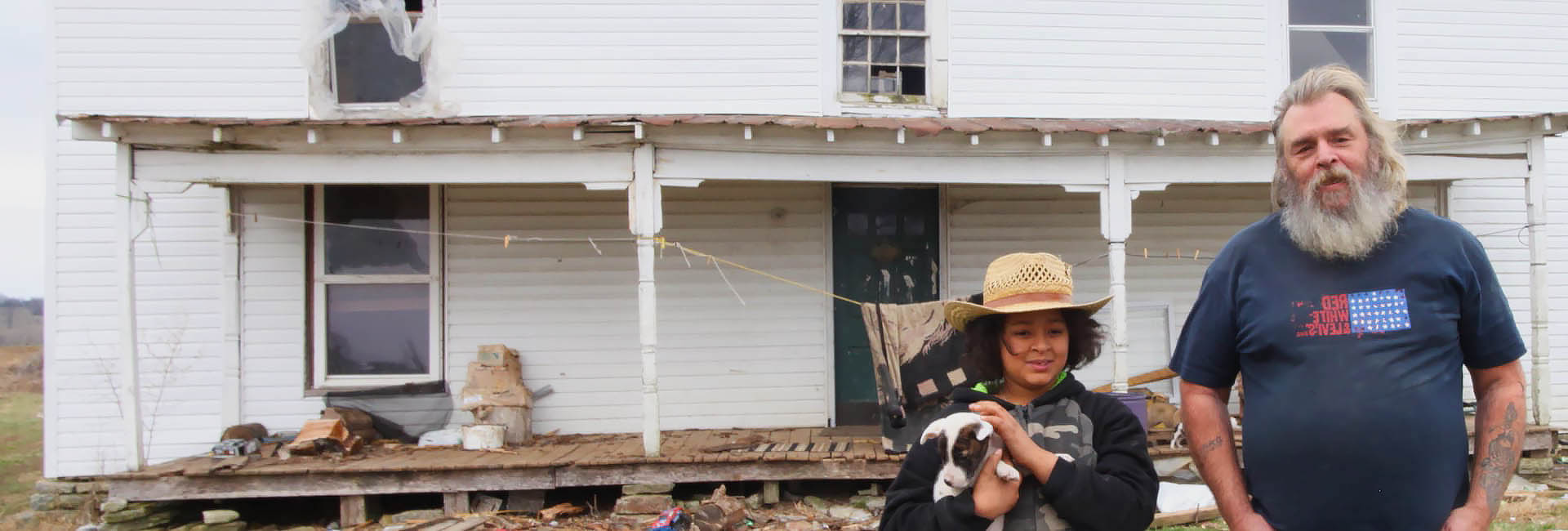 A man and boy with a dog standing in front of a house