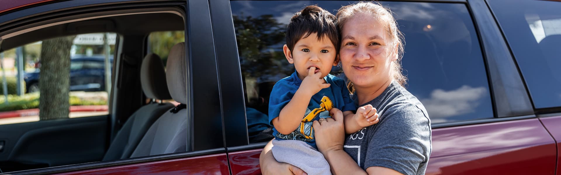 Joyce and her child standing outside in front of a vehicle