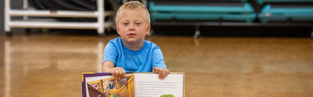 A boy holding a book in a gym