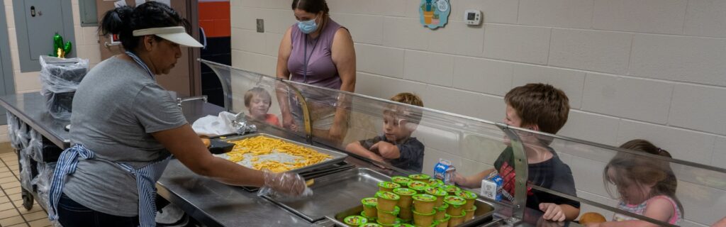 Children in line in a school cafeteria getting food