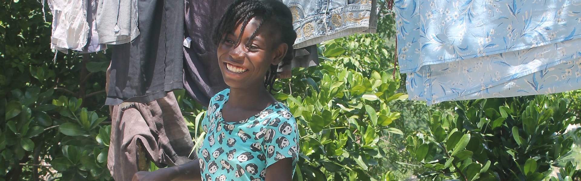 A young girl standing near laundry outdoors