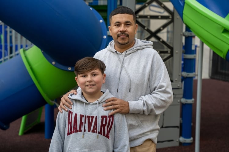 Marco standing with his son outdoors