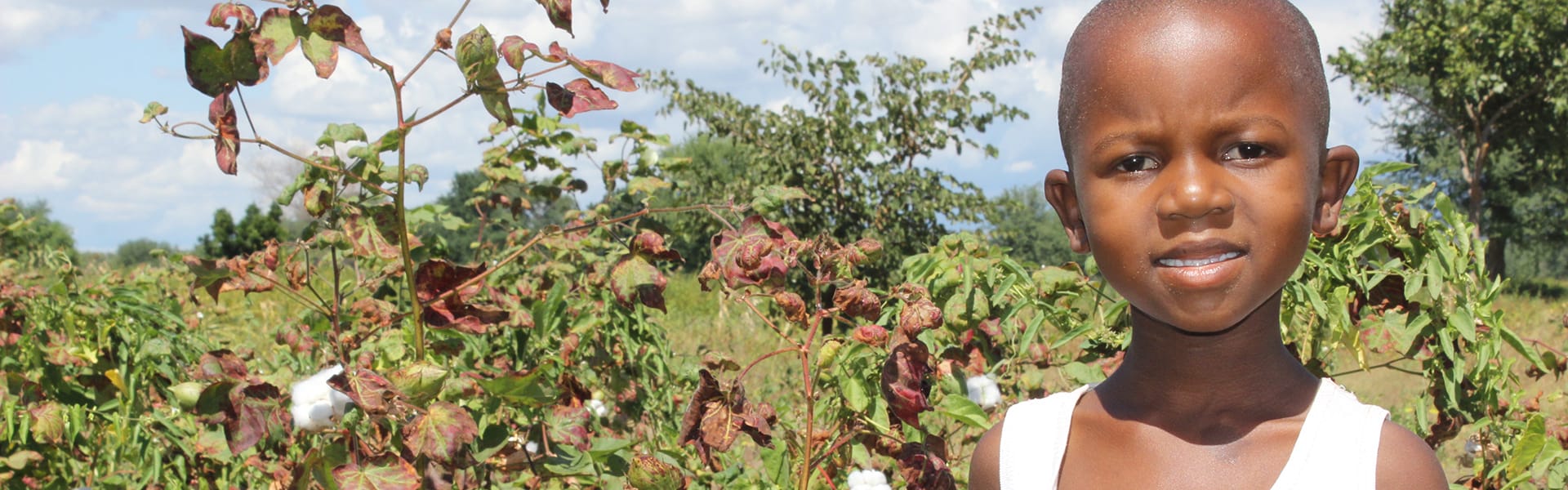 A young girl standing outdoors in front of a field