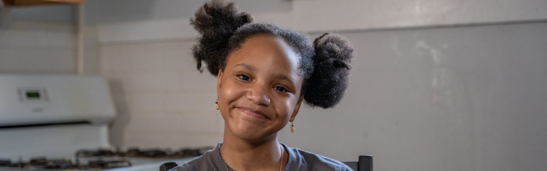 A girl smiling while sitting in the kitchen