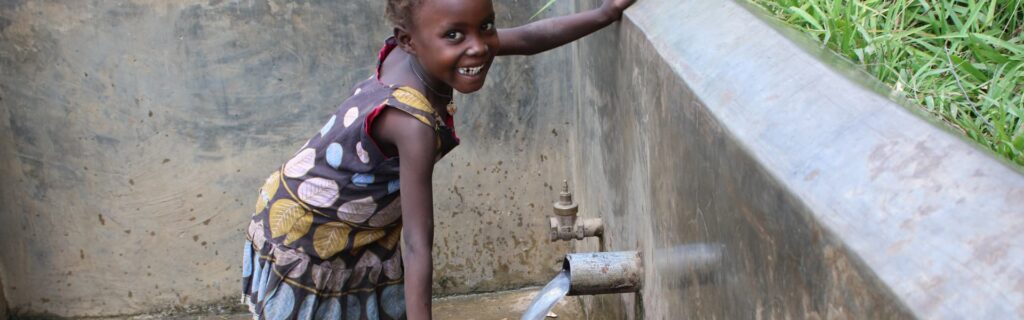 A child smiling in Africa while getting water