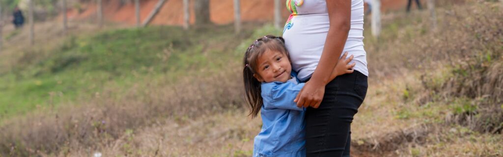 A child hugging her mother who is pregnant