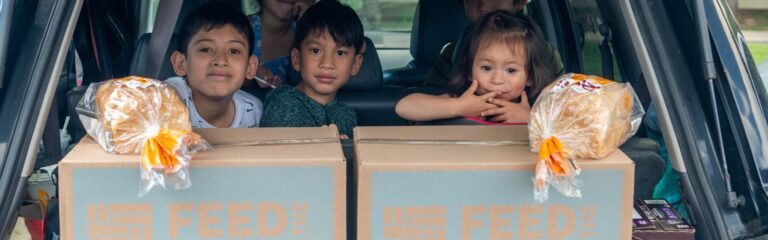 Children in the back of an sux with feed the children boxes