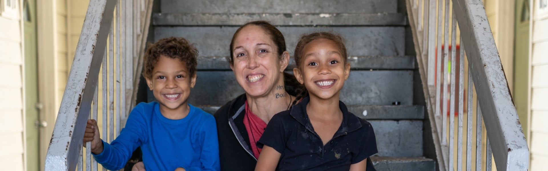 A mother and two children sitting on stairs outdoors