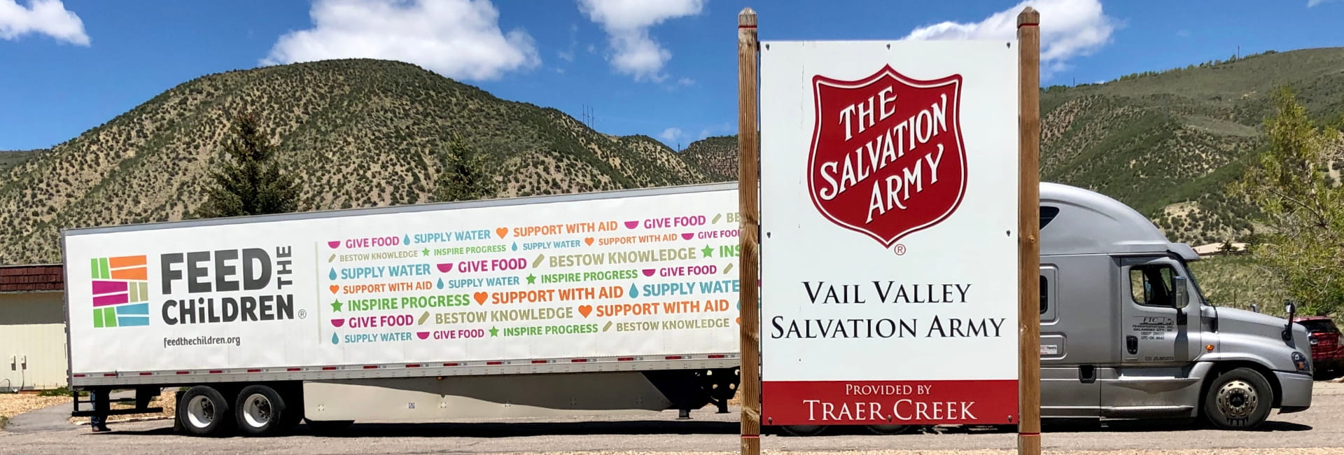 A feed the children semi near a salvation army sign on a road