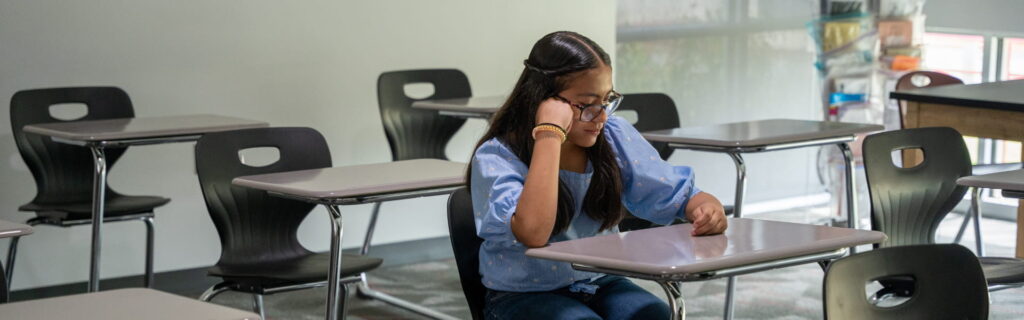 A young girl sitting in a school classroom