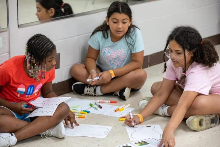 Children sitting on the floor with educational material