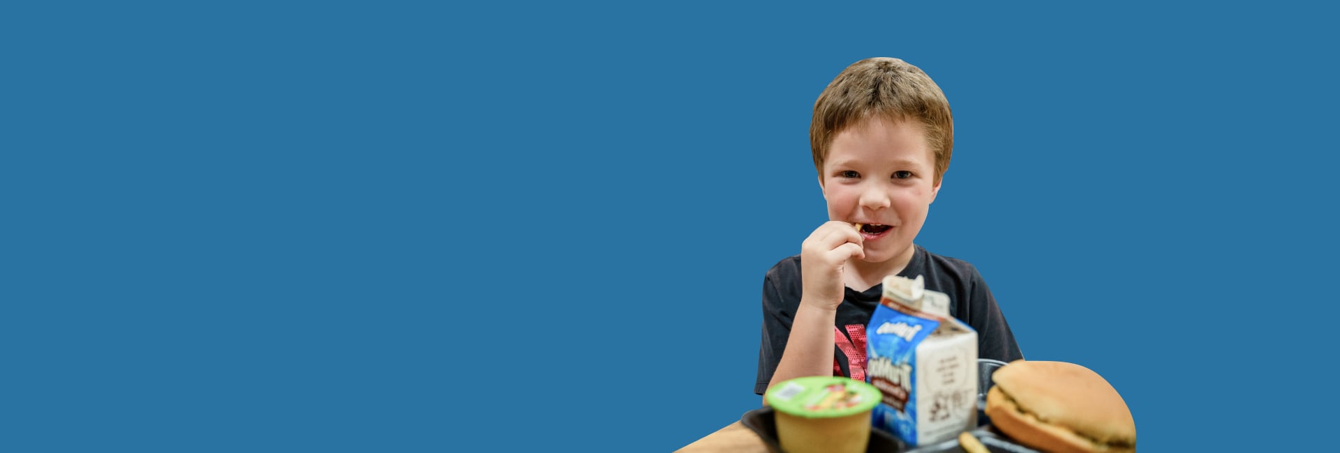 A boy with food in front of a blue background