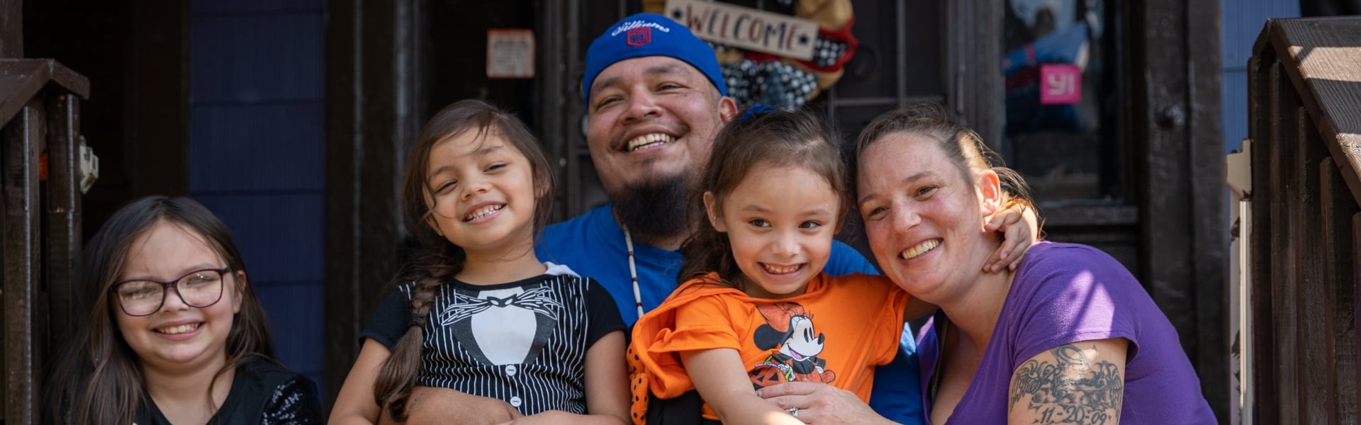 A family smiling sitting on the porch